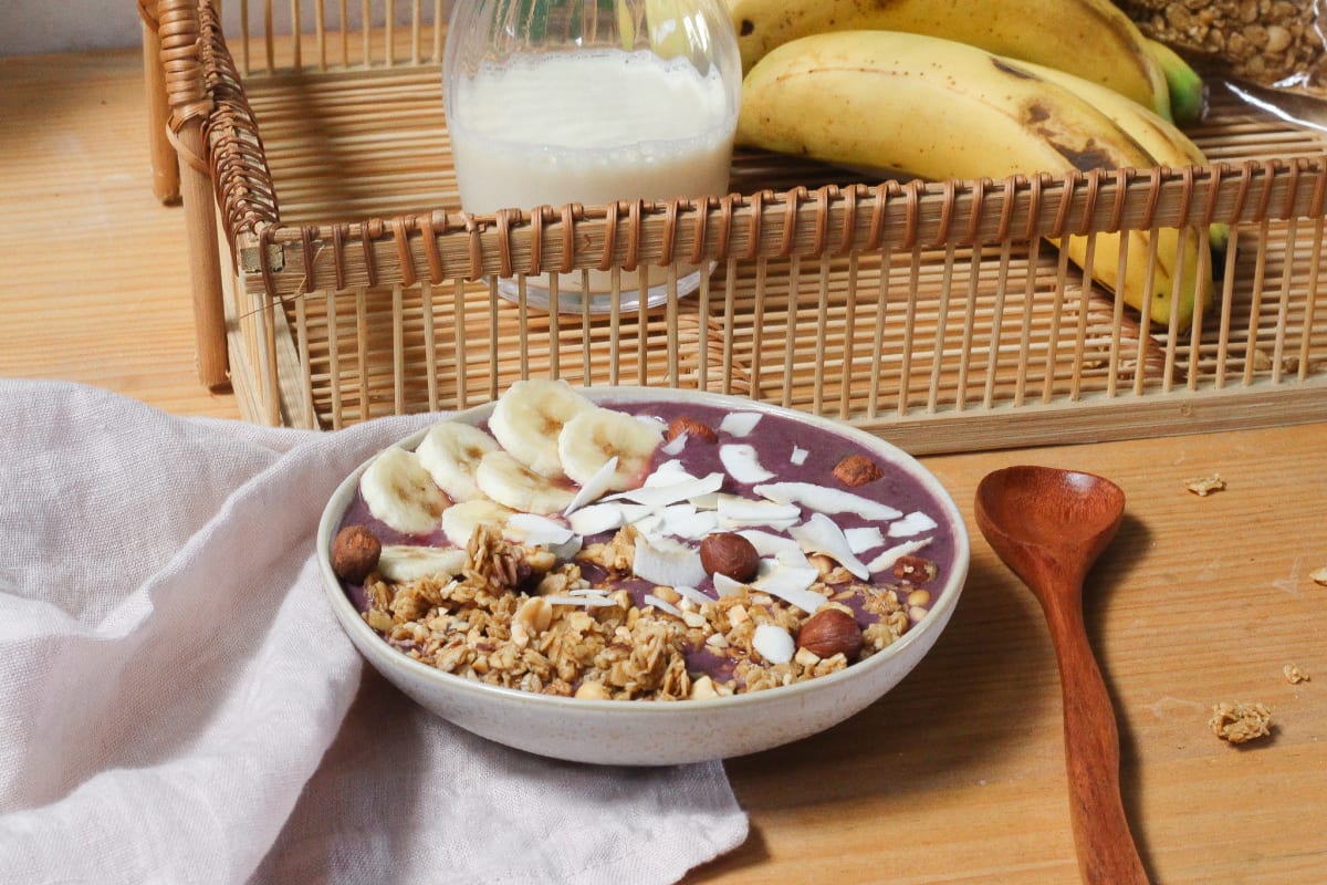 Açaï bowl banane et coco, avec lait végétal sur table de petit-déjeuner