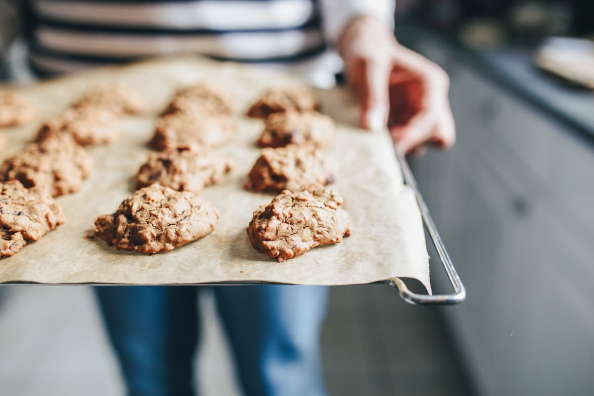 Grille de four avec des cookies au muesli, tenue par une jeune femme