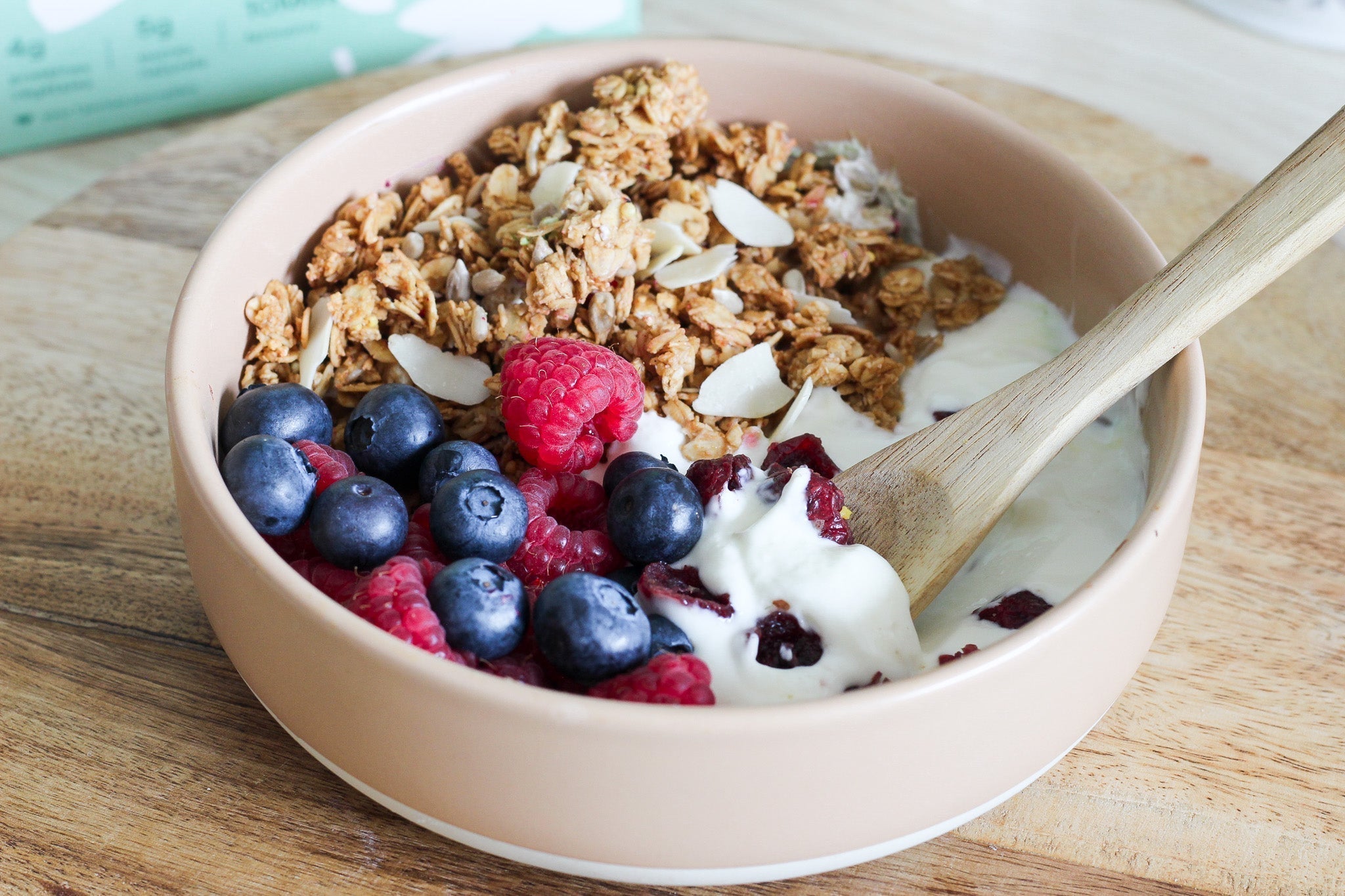 Granola bowl aux fruits rouges pour le petit-déjeuner avec une cuillère en bois