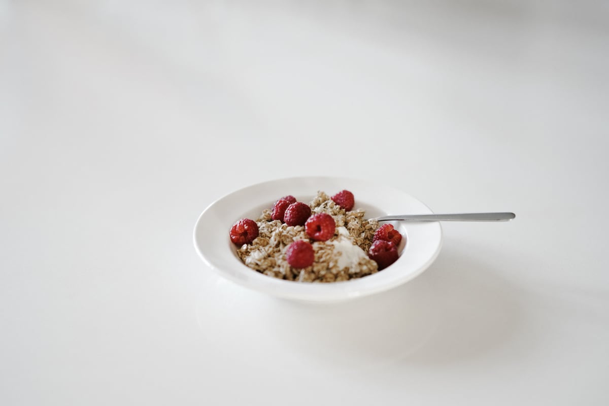 Bol de muesli avec des framboises entières en topping pour un petit-déjeuner plein de bienfaits