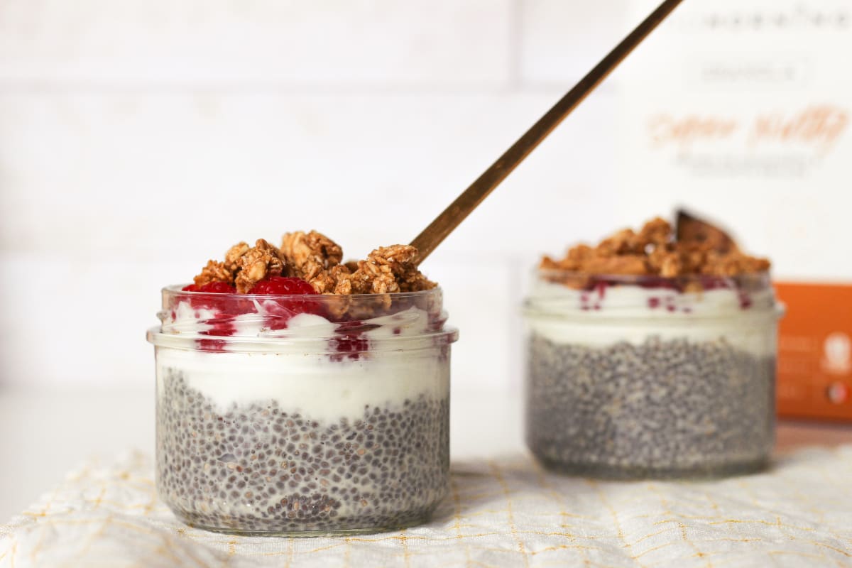 Deux puddings de chia avec de la framboise, du granola et du beurre de cacahuète en topping