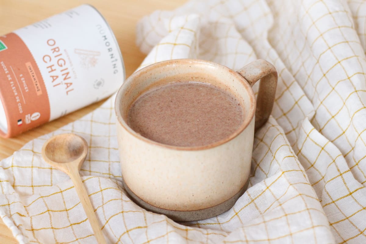 Mug de chai latte maison avec une cuillère en bois sur une table en bois
