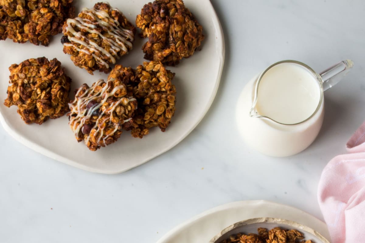 Assiette de cookies au granola sur une table de petit-déjeuner avec un pichet de lait végétal