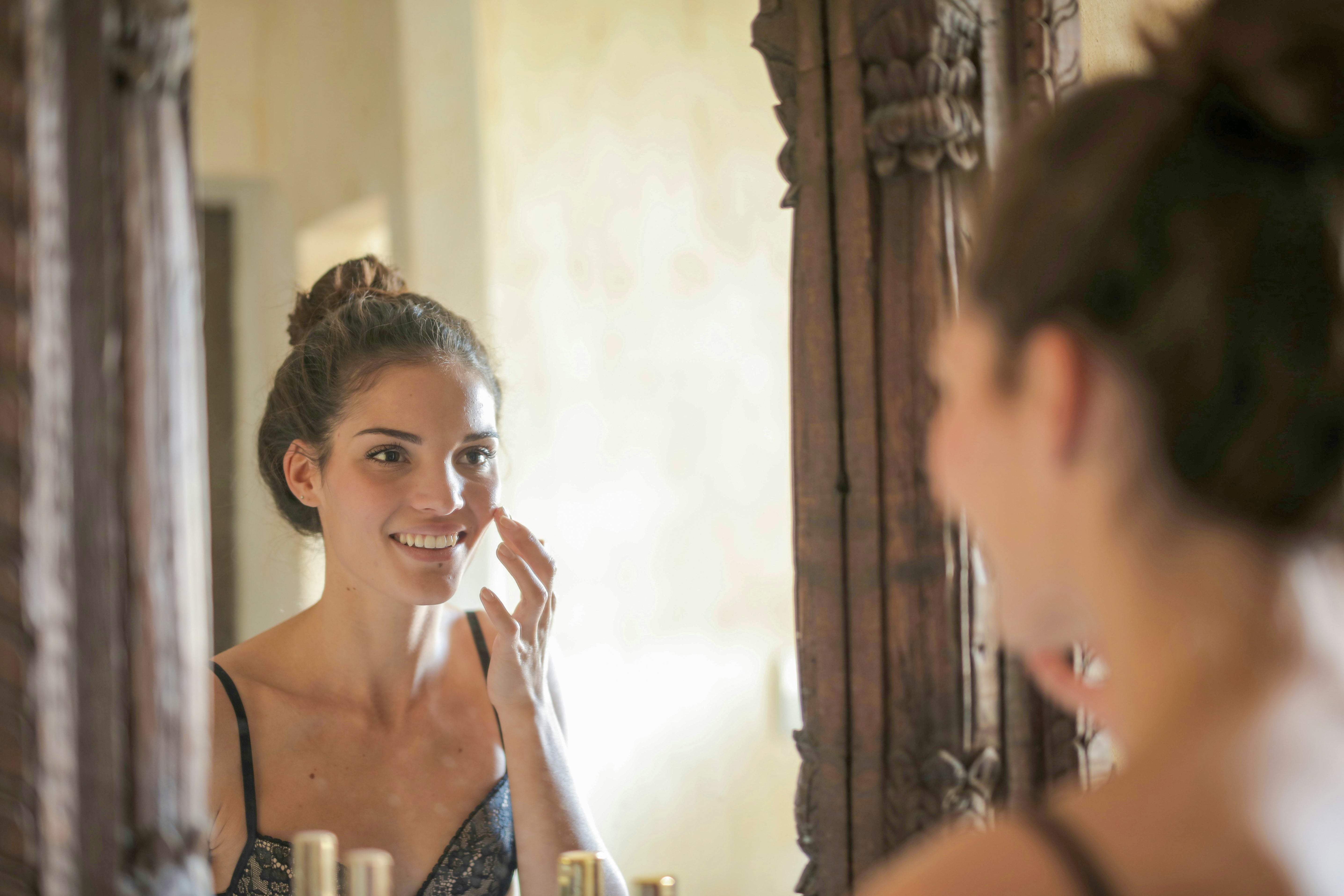 Jeune femme appliquant une crème pour le visage, symbole d'une routine in & out pour une belle peau