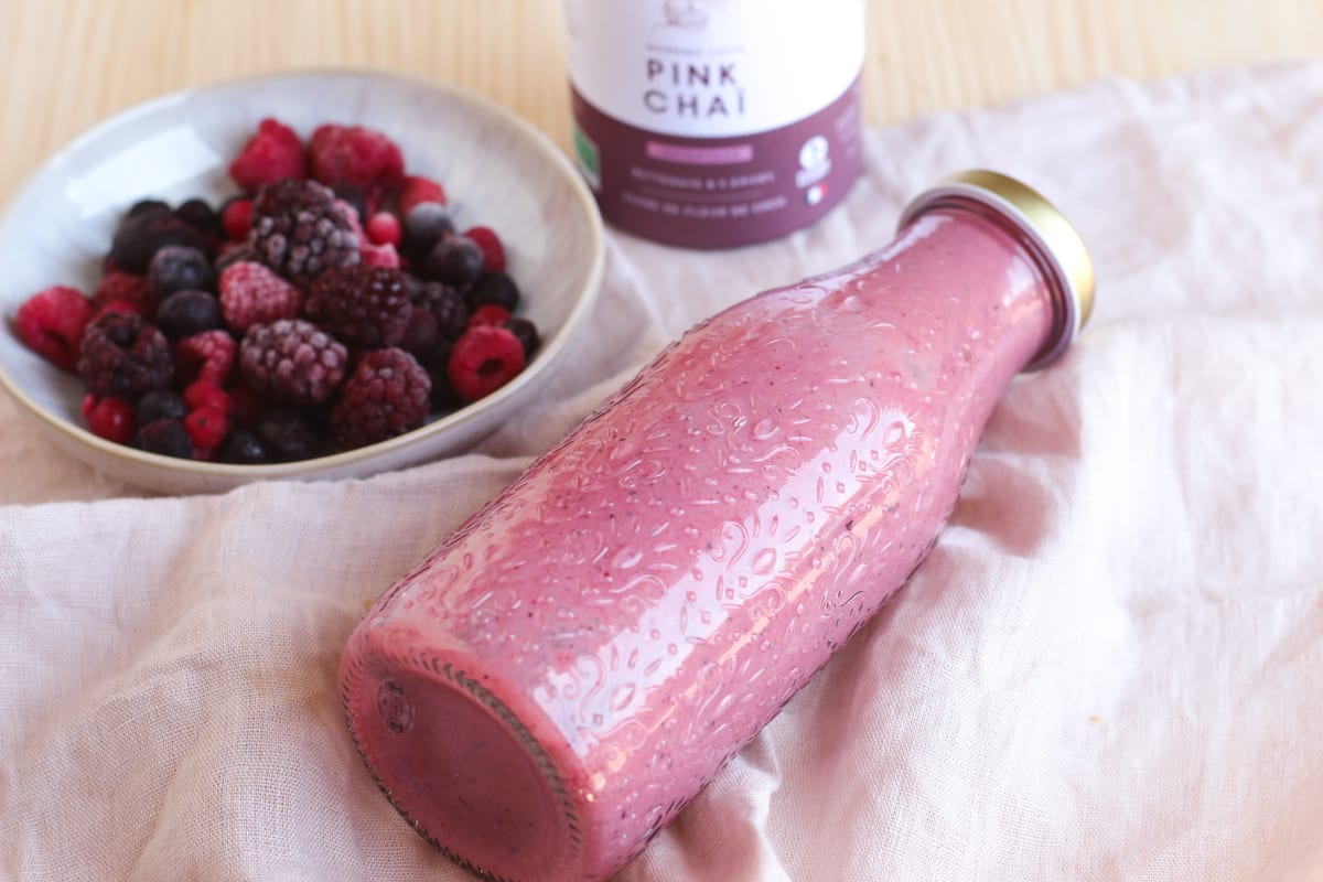 Bouteille de smoothie aux fruits rouges à côté d'un bol de fruits rouges