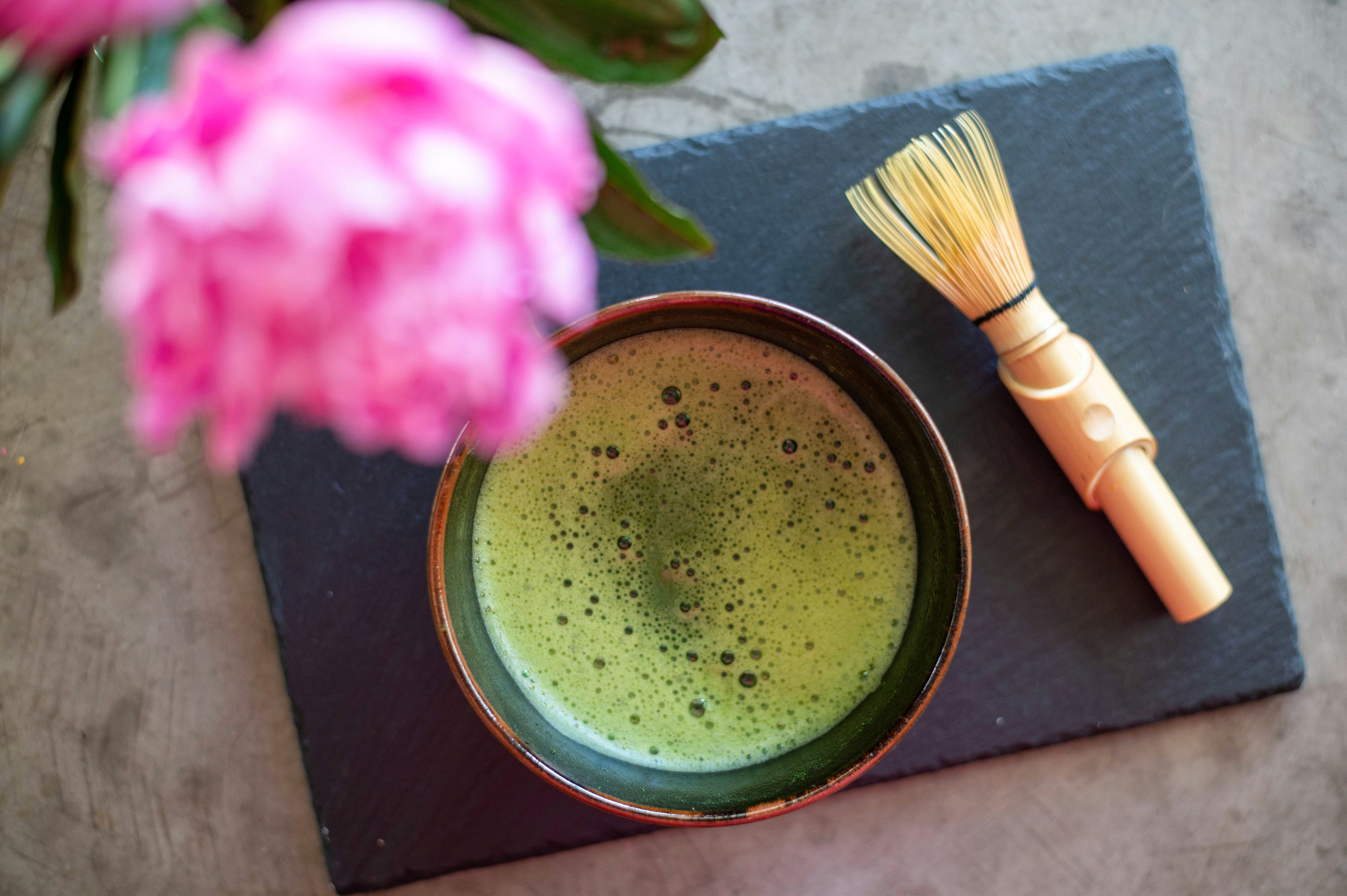 Bol de thé matcha préparé, avec un fouet en bambou (chasen) posé à côté