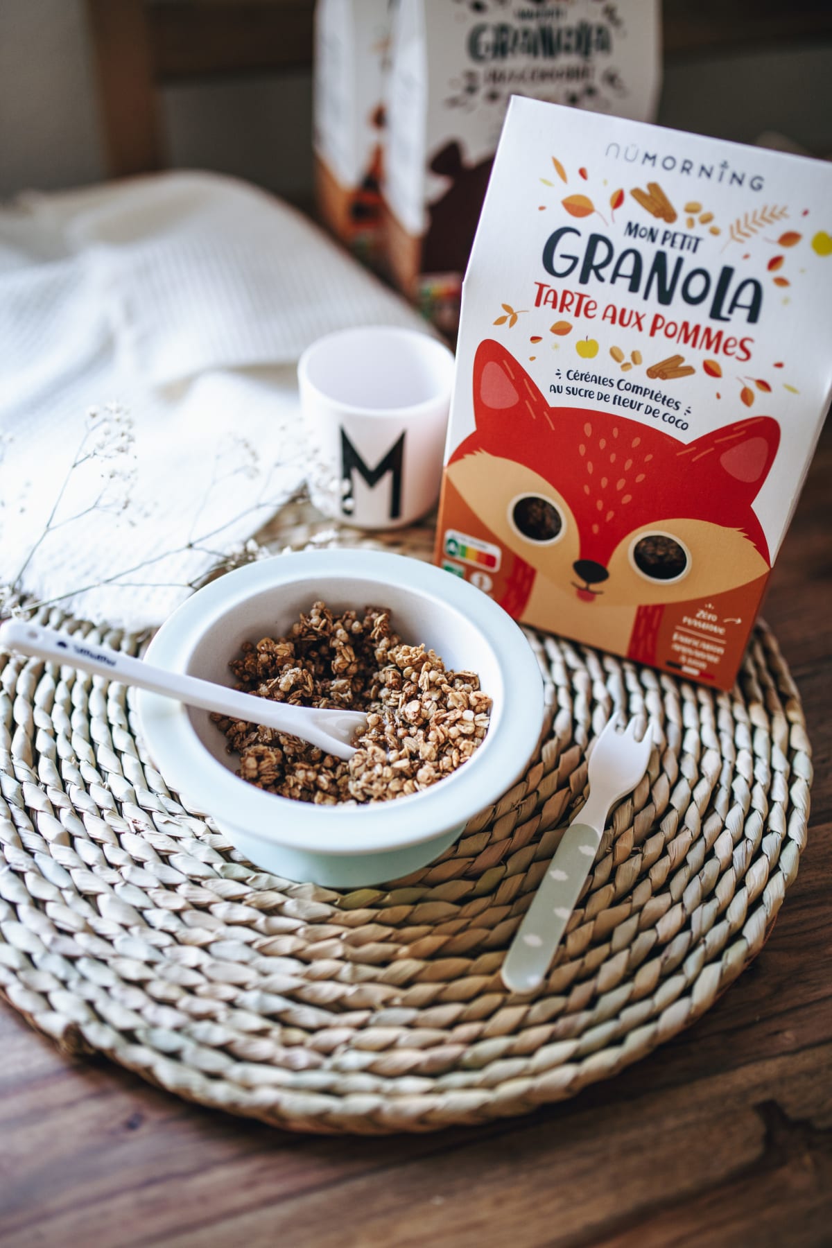Bol de granola pour enfant à côté d'un paquet de granola et d'une fourchette sur un set de table