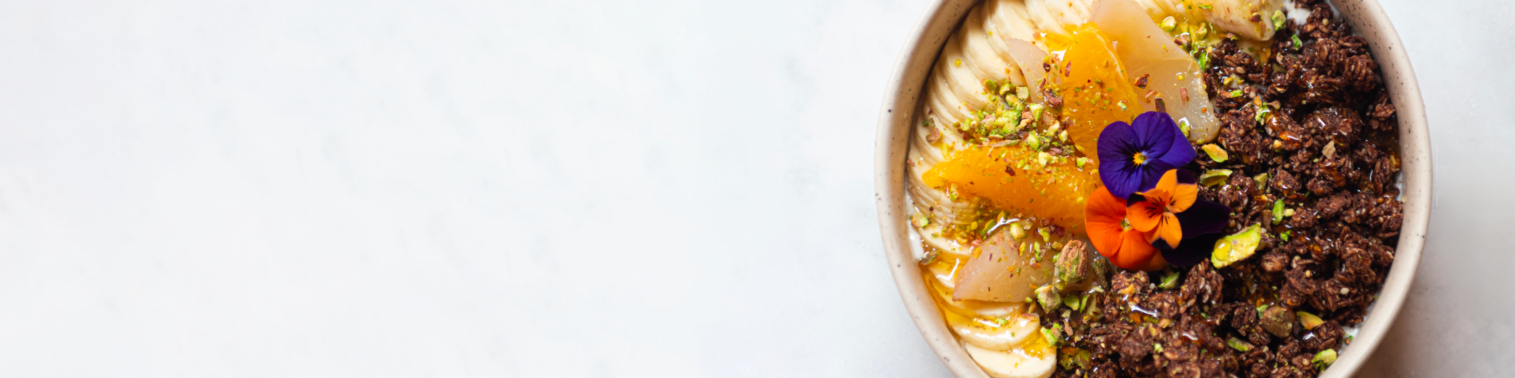 Bol de granola bio croustillant avec yaourt, fruits frais et pistache pour le petit-déjeuner