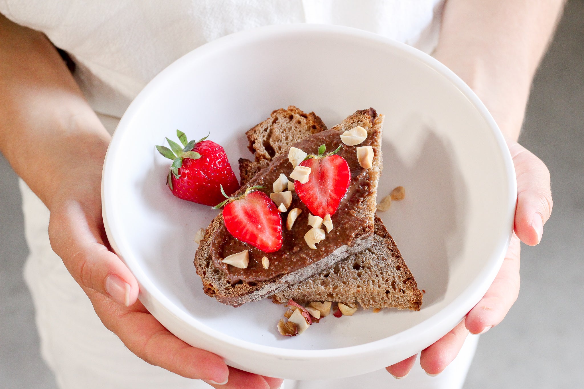 Deux tartines de pain complet avec de la pâte à tartiner bio au chocolat nümorning et des fraises
