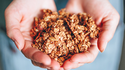 Granola bio croustillant tenu dans les mains, prêt à être dégusté au petit-déjeuner