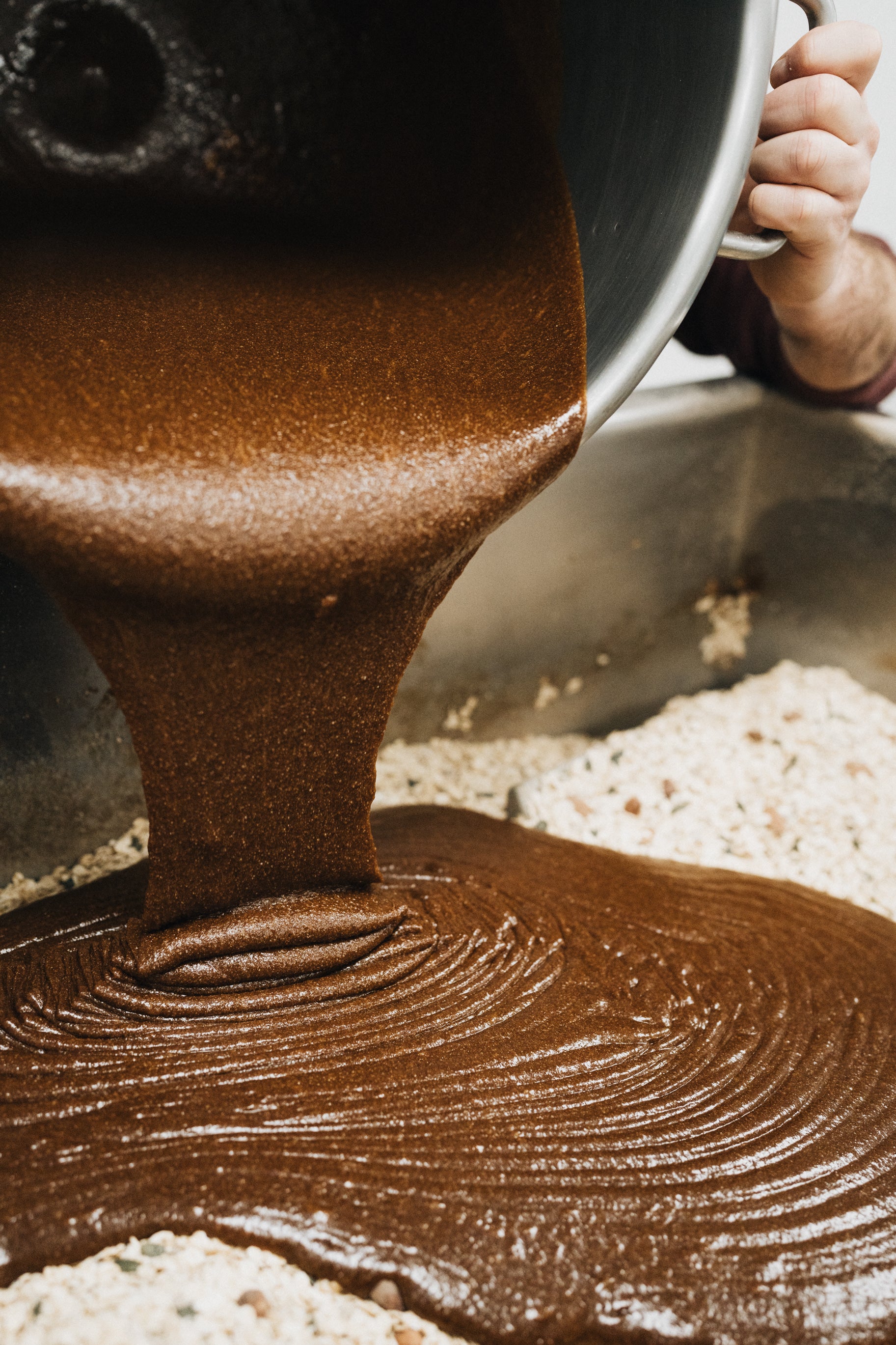 Préparation d'un granola au chocolat : de la pâte chocolatée versée sur des flocons d'avoine