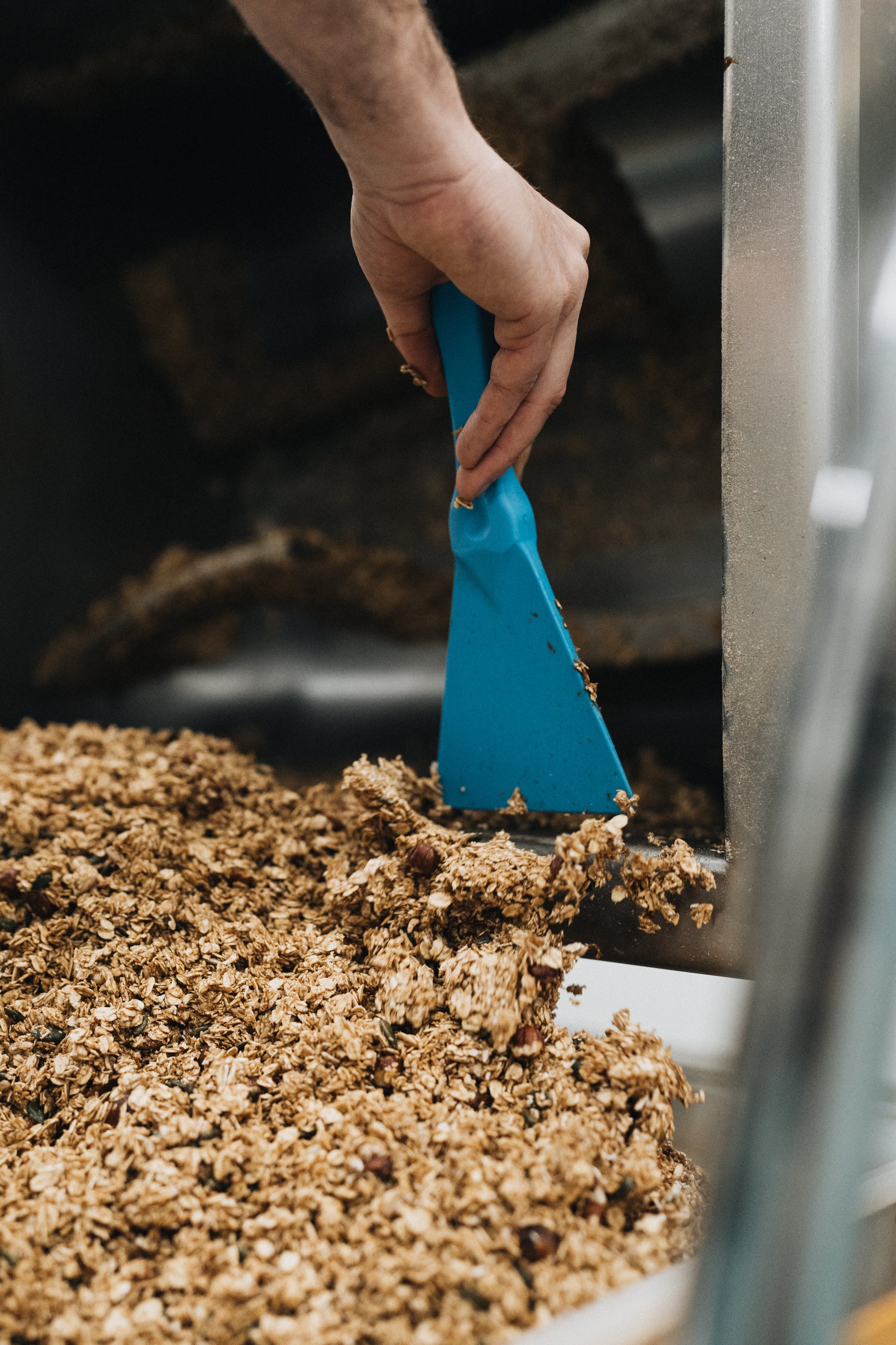 Raclage du granola cuit dans la cuve de production de l'atelier artisanal de nümorning