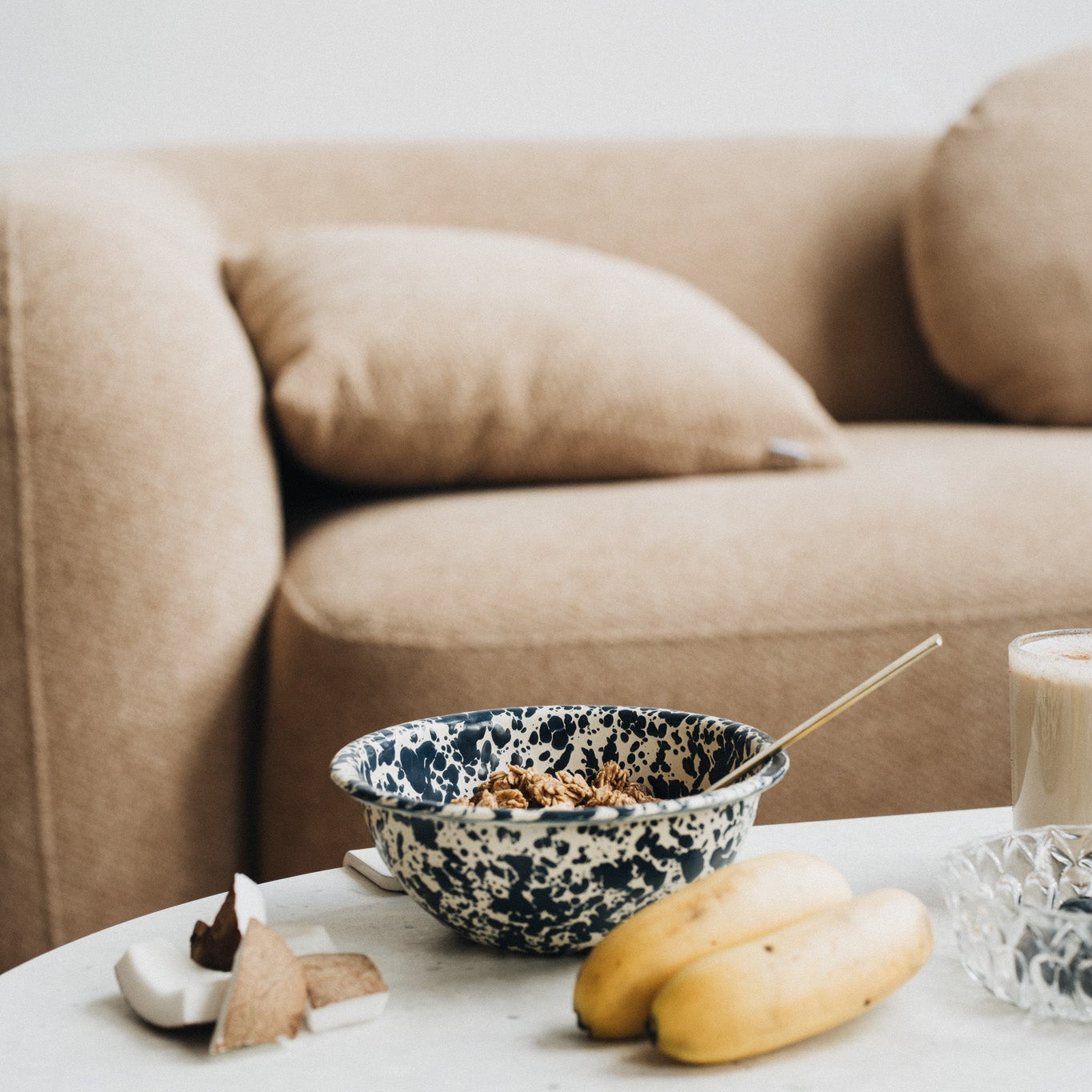 Bol de granola posé sur une table avec des bananes et de la noix de coco.