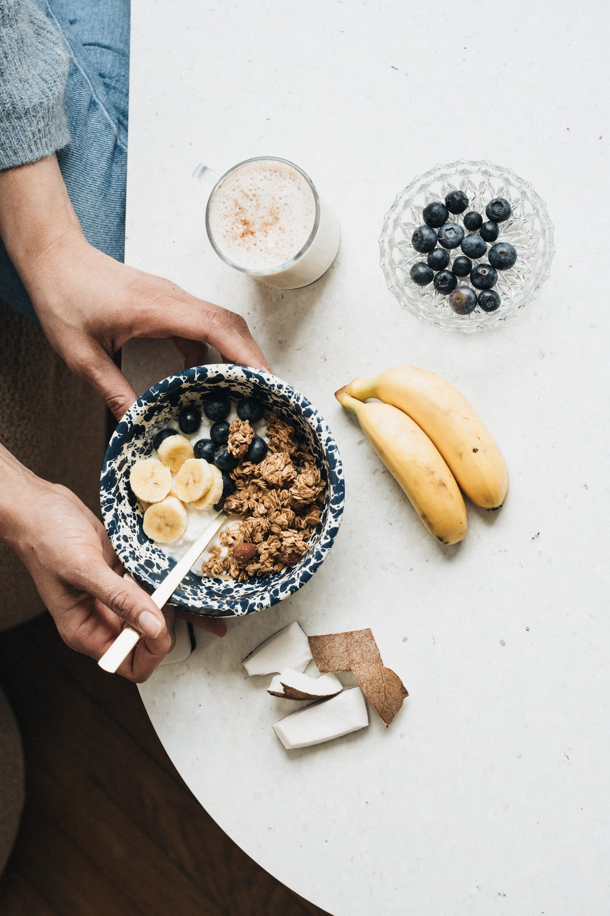 Une table de petit-déjeuner avec un granola bowl à la banane, un verre de boisson petit-déjeuner et des fruits