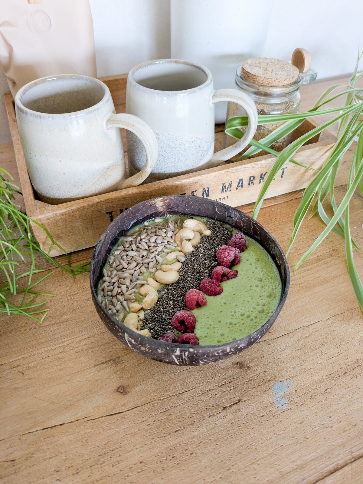 Smoothie bowl au matcha avec des graines de chia et de tournesol, des framboises et cajous