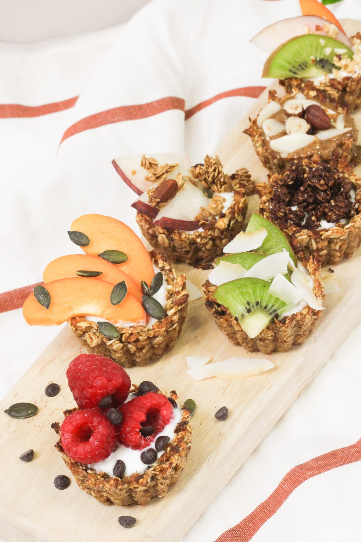 Sept tartelettes sans gluten et véganes garnies de kiwi, framboises, copeaux de coco et pomme