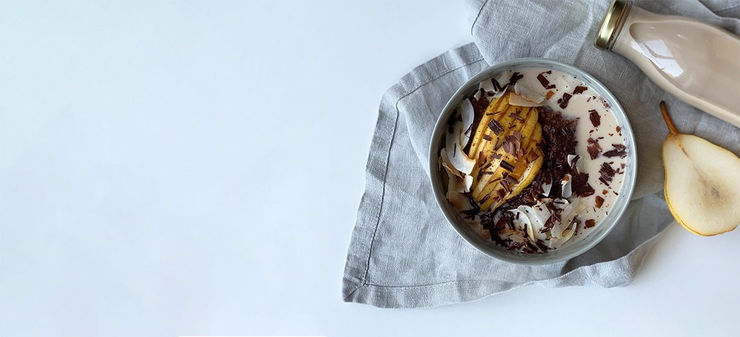 Bol de porridge bio au lait végétal avec poire, coco et copeaux de chocolat pour le petit-déjeuner