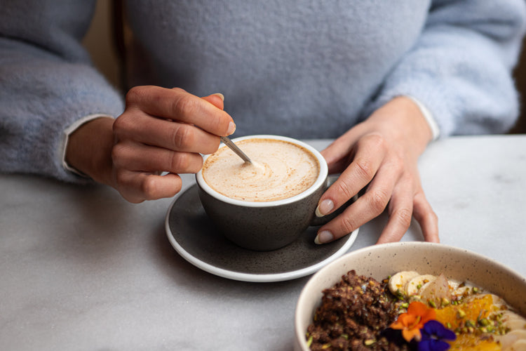 Tasse de latte nümorning sur table en marbre, dégustée avec un bol de granola