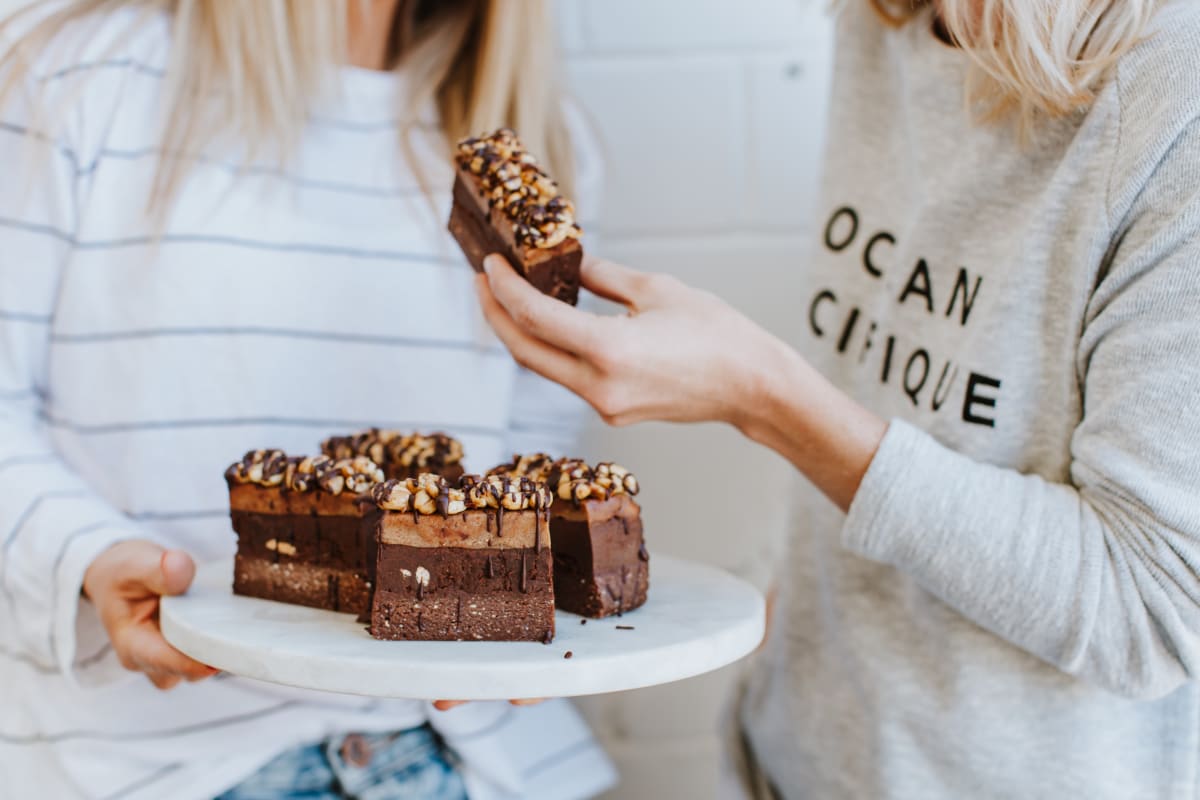 Deux femmes se servent une part de gâteau au chocolat sur un plateau Image
