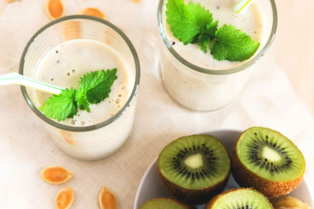 Deux verres de smoothie à la menthe avec une assiette de kiwis coupés en moitiés