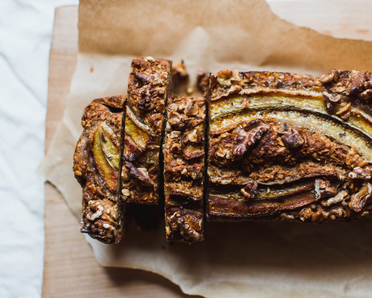 Banana bread sur une planche à découper, avec trois parts déjà découpées