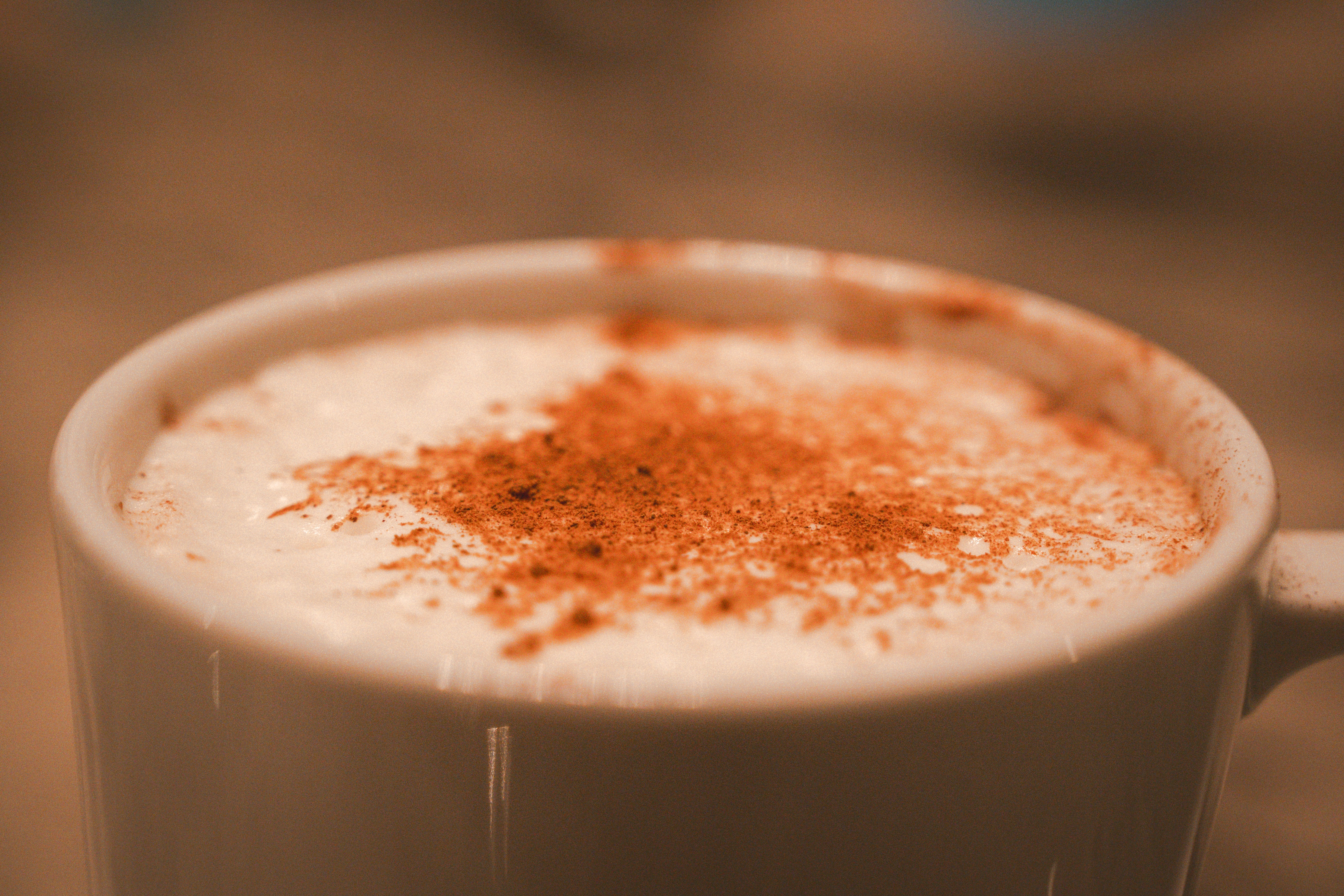 Gros plan sur un mug de chai latte maison avec de la cannelle en poudre sur la mousse de lait