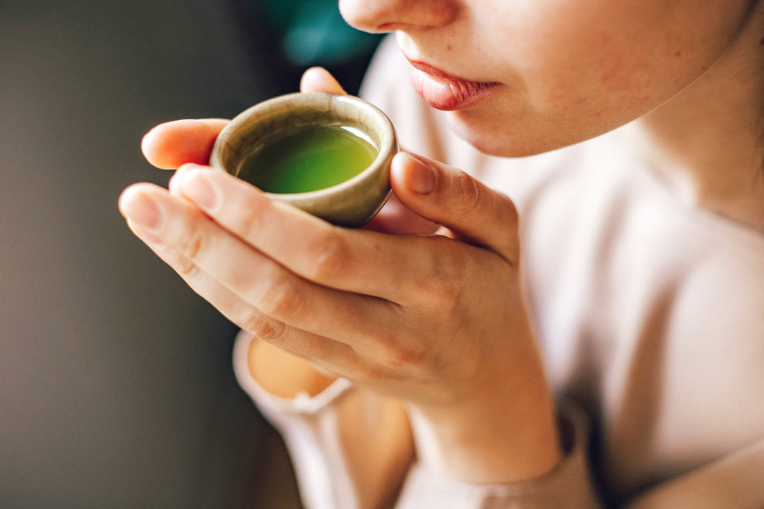 Une femme boit du thé matcha pour ses bienfaits pour la peau