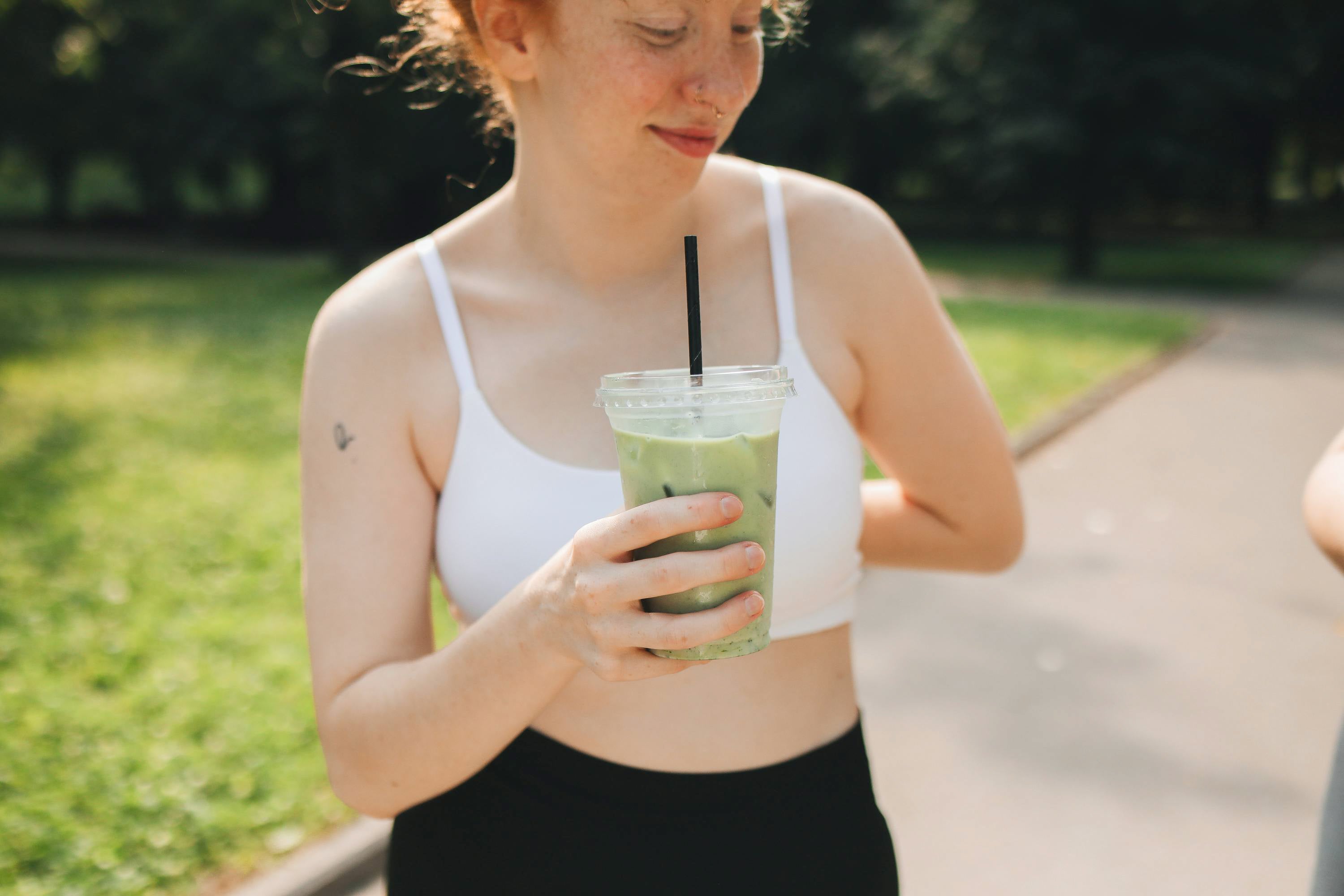 Une jeune femme buvant un matcha latte en extérieur Image