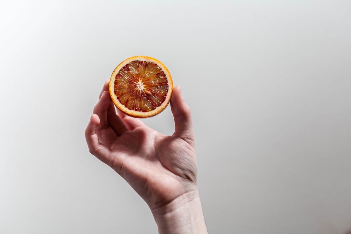 Moitiée d'orange tenue par une main, comme exemple d'aliment bénéfique pour le microbiote intestinal Image