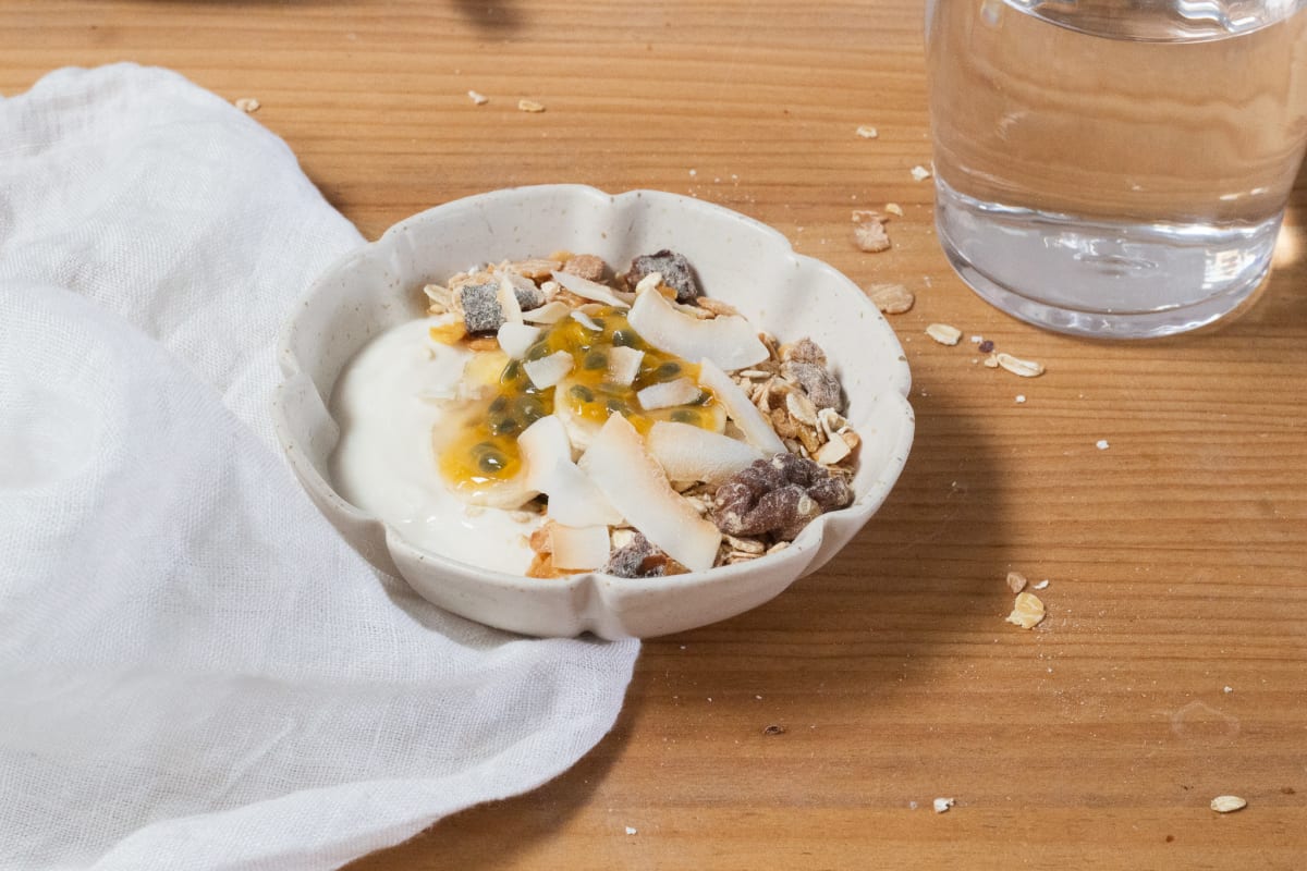 Bol de muesli maison avec yaourt végétal, copeaux de coco et dattes séchées