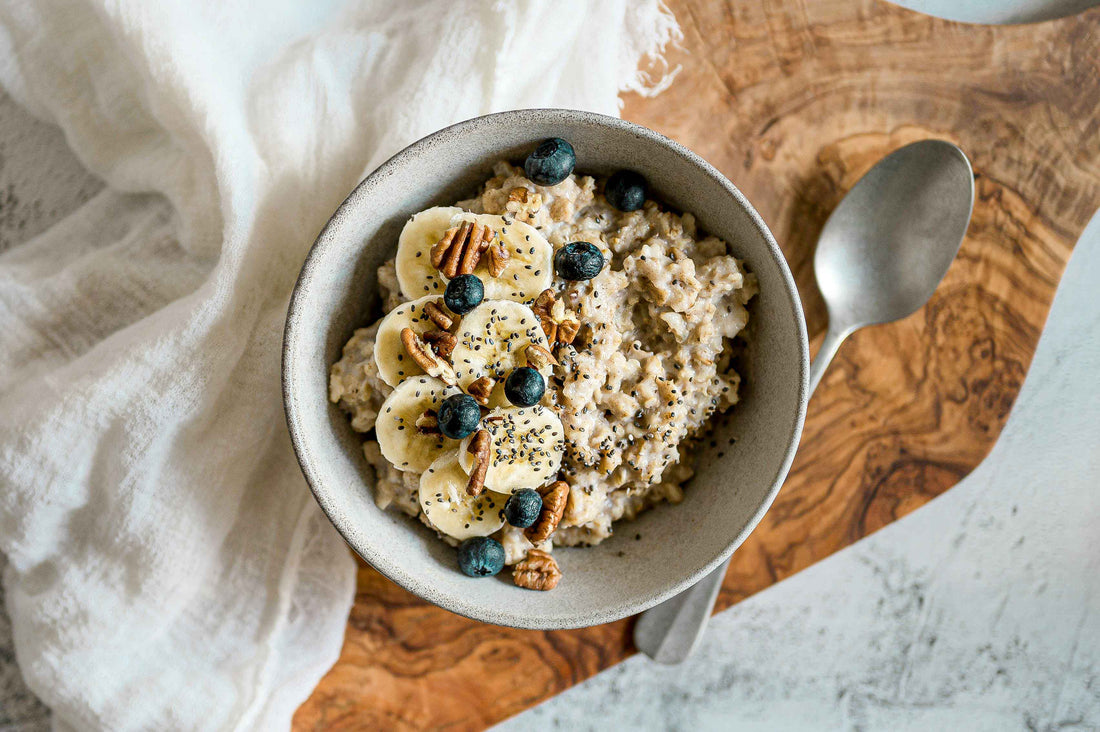 Bol de porridge protéiné avec des tranches de banane, des myrtilles et des noix de pécan