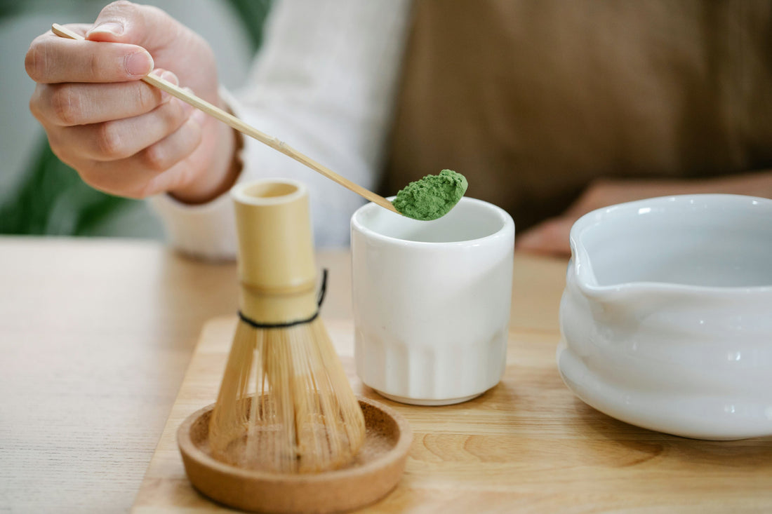 Du thé matcha dans une cuillère pendant la préparation d'un matcha avec un petit bol et un fouet