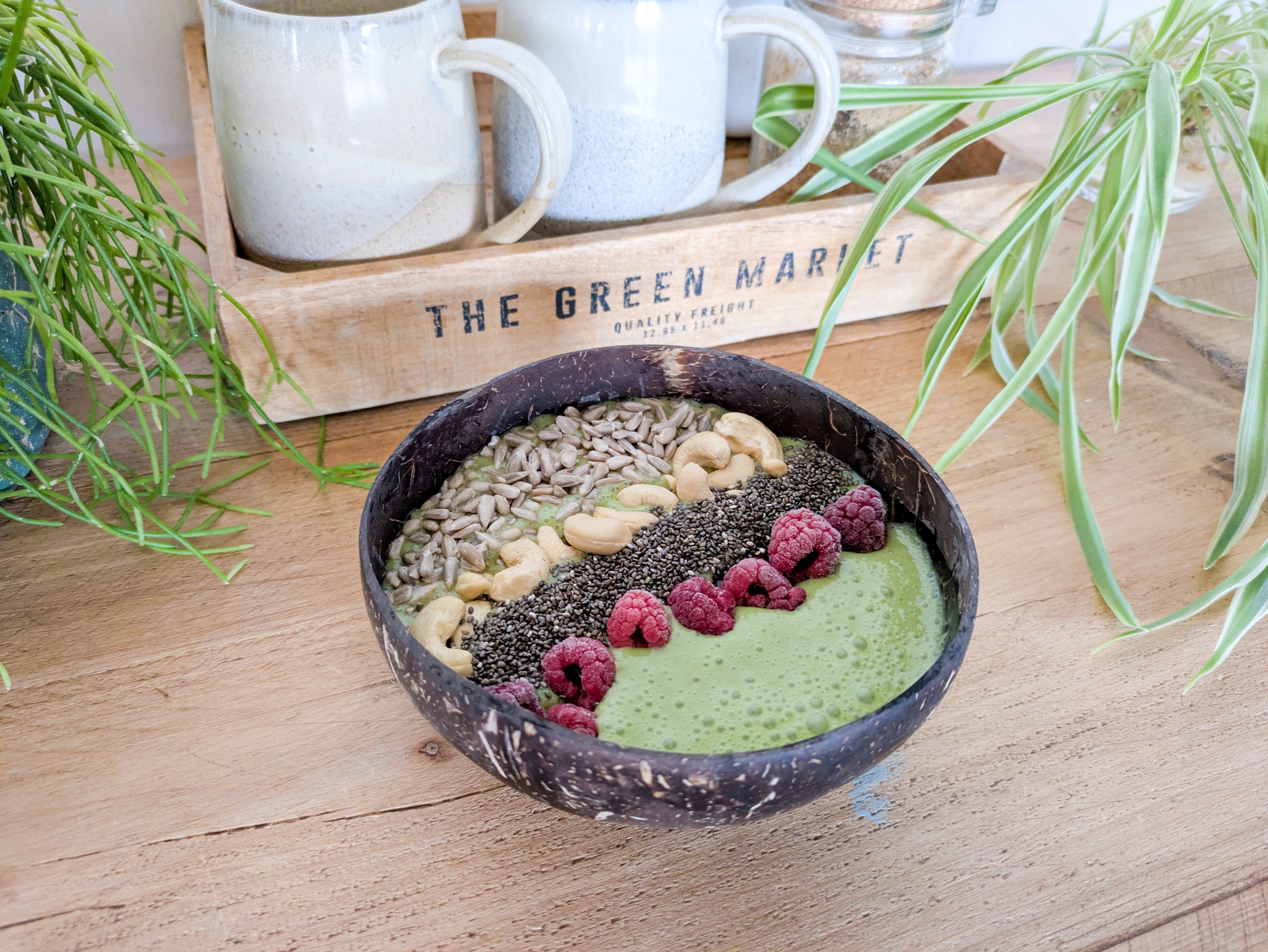 Gros plan sur un smoothie bowl au matcha avec framboises, noix de cajou et graines de chia
