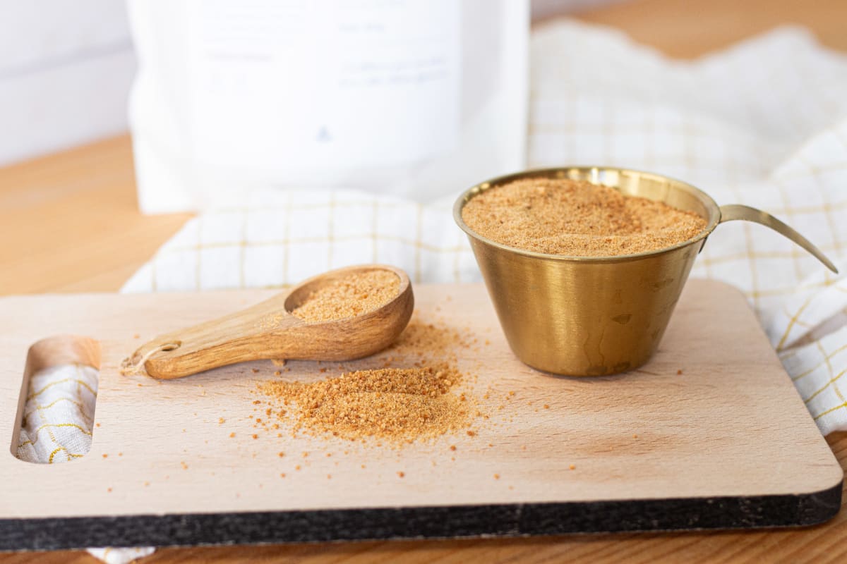 Sucre de fleur de coco dans un pot, sur une planche à découper avec une cuillère en bois