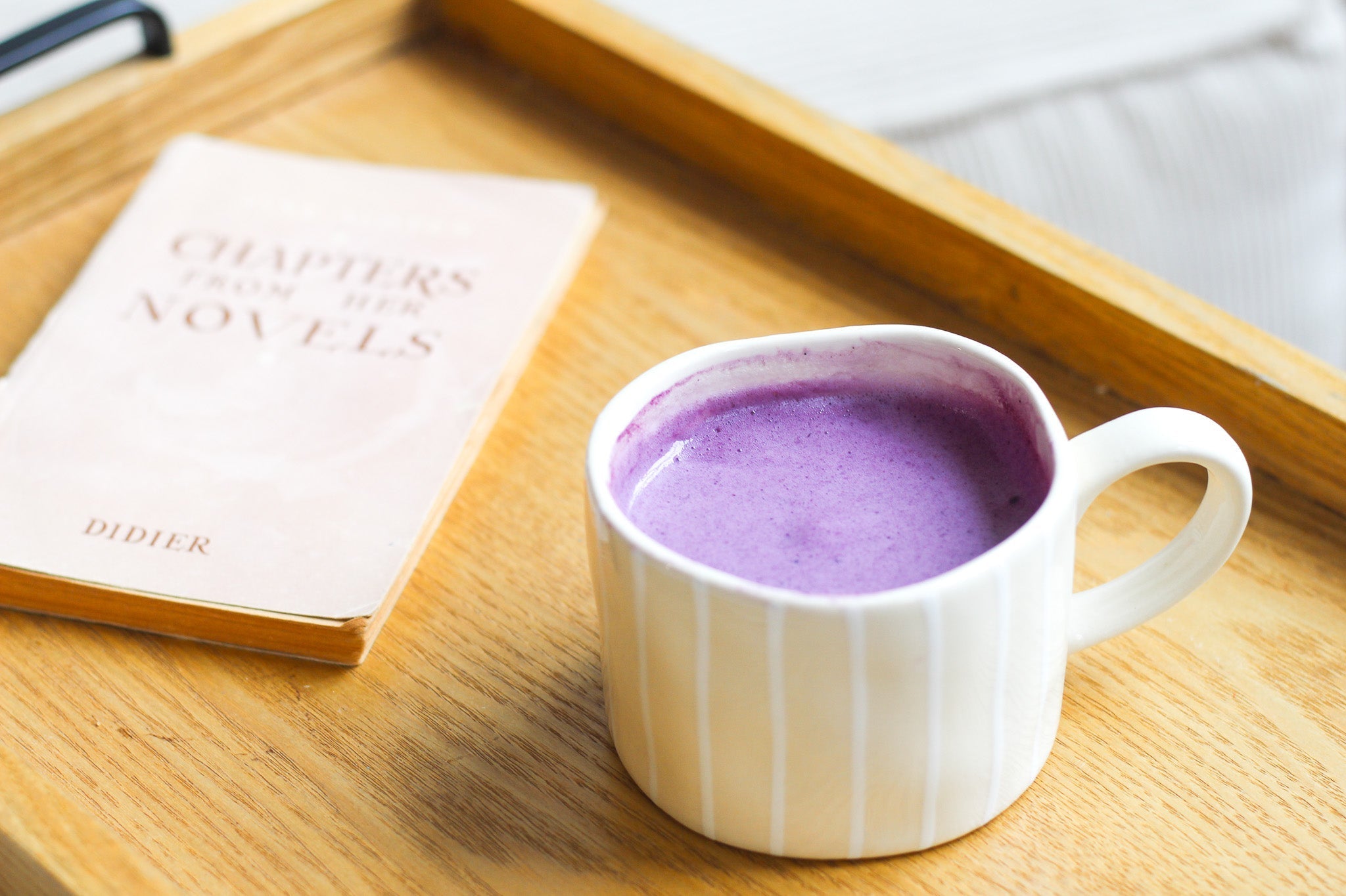 Une tasse de ube latte sur un plateau avec un livre