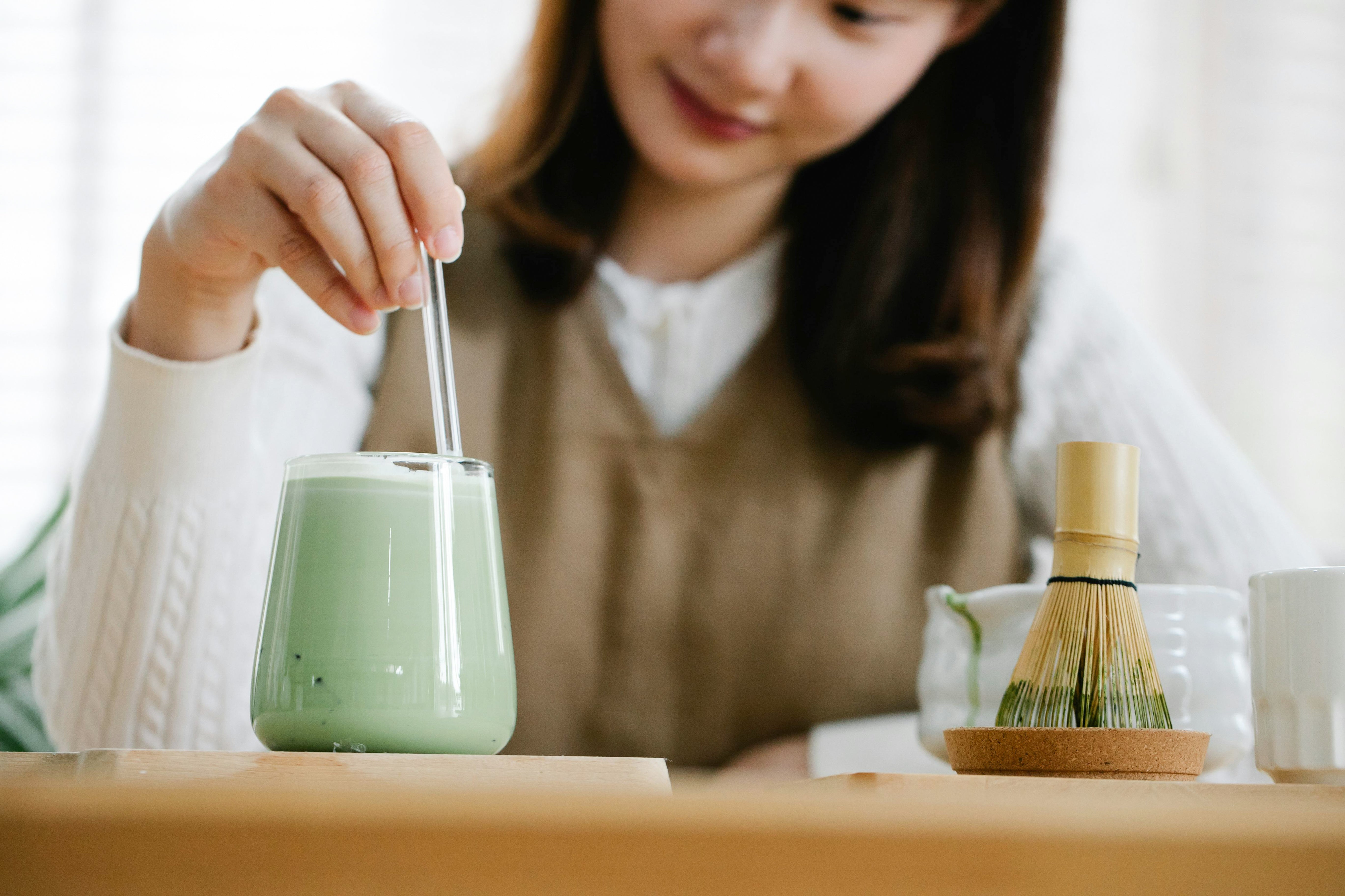 Une femme mélange son matcha latte avec une cuillère