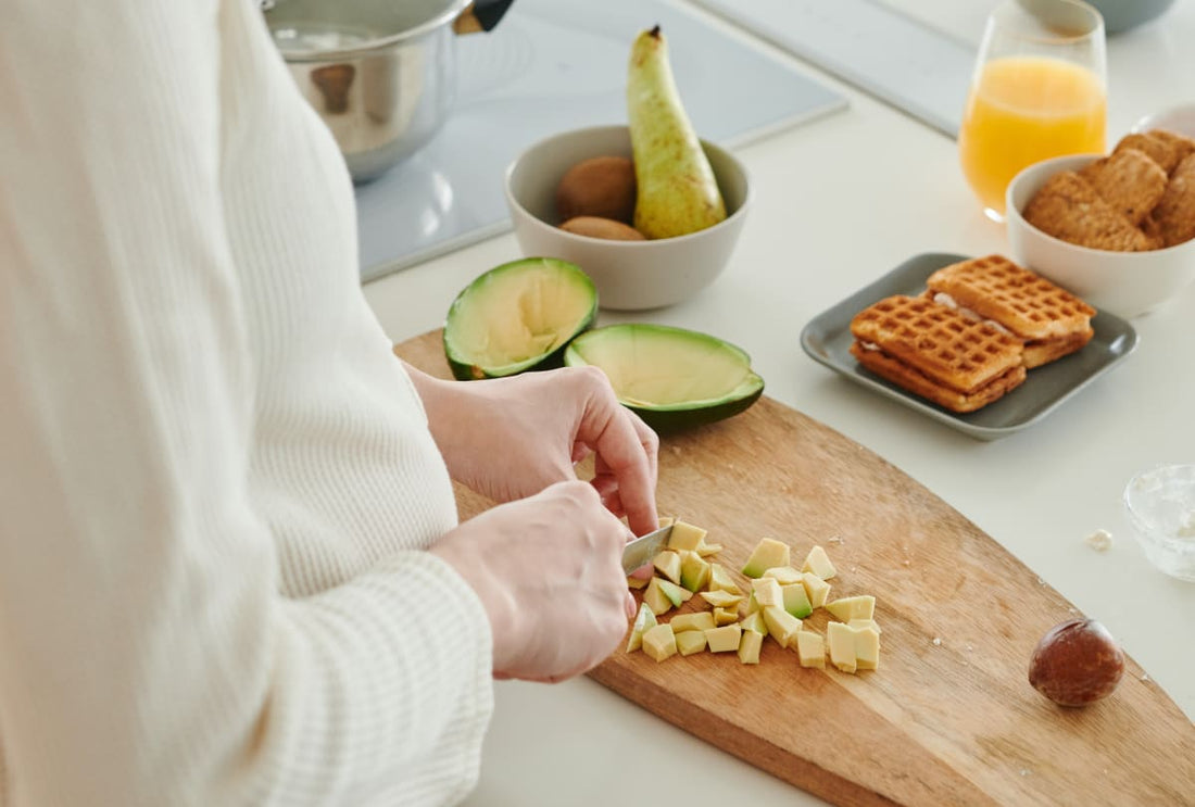 Jeune femme découpant un avocat en petits morceaux sur une planche à découper