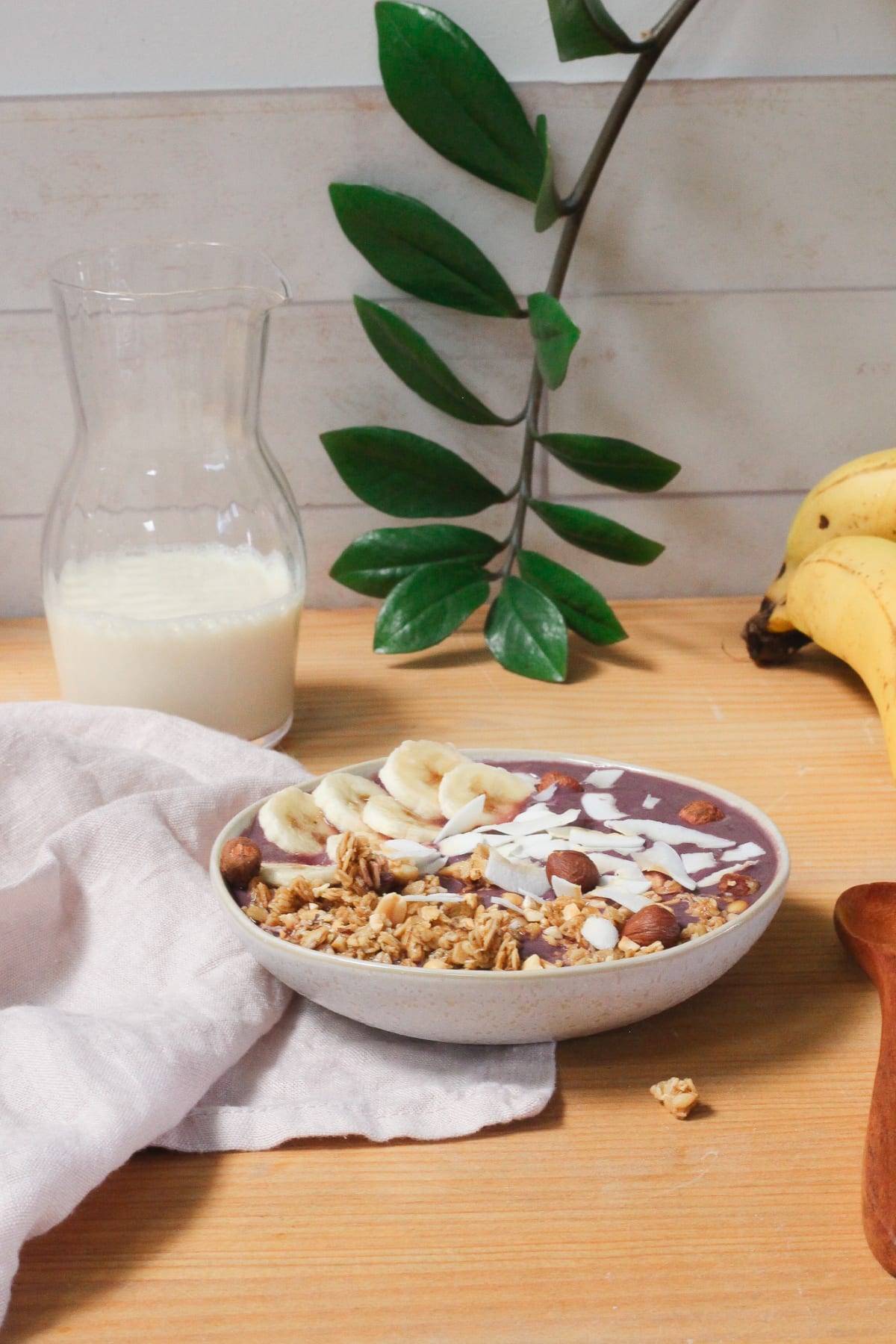 Açaï bowl banane et coco, avec carafe de lait végétal et bananes en fond