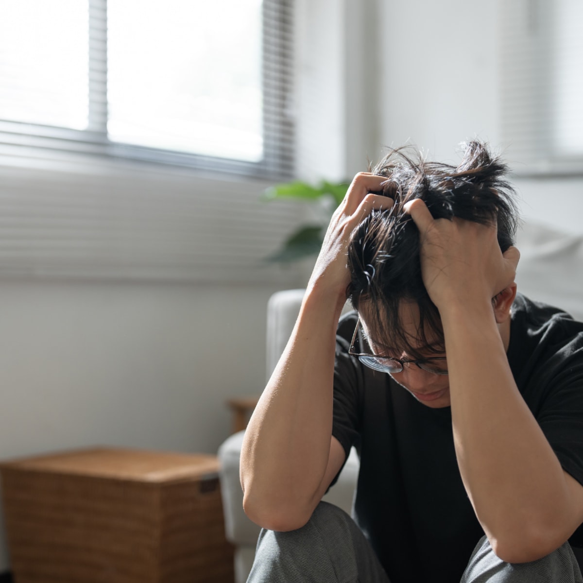 Jeune homme anxieux, assis, qui se tient la tête