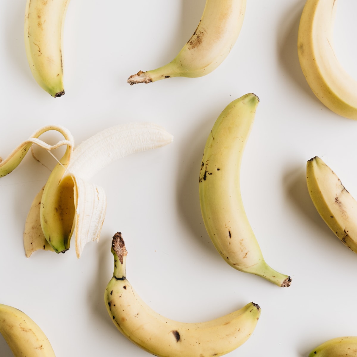 Bananes sur une table, dont une avec la peau à moitié retirée