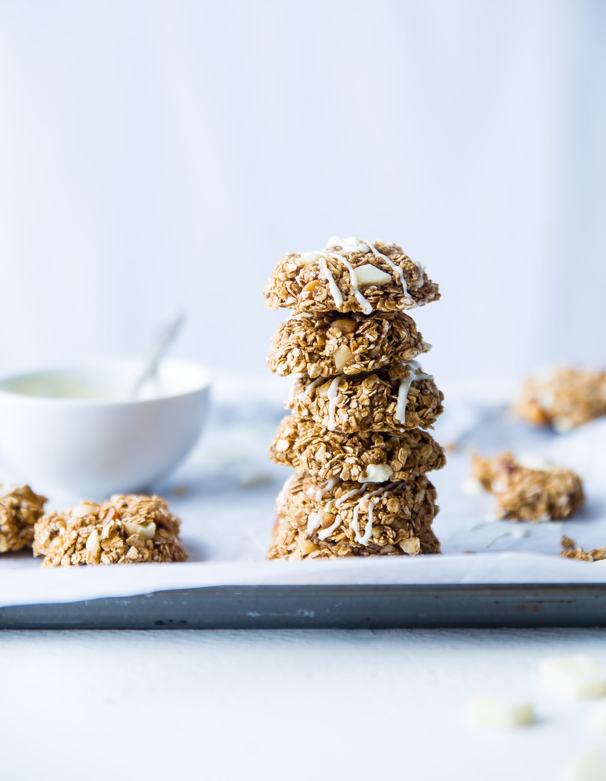 Pile de cookies à l'avoine sur une feuille de papier cuisson, avec un bol en arrière plan