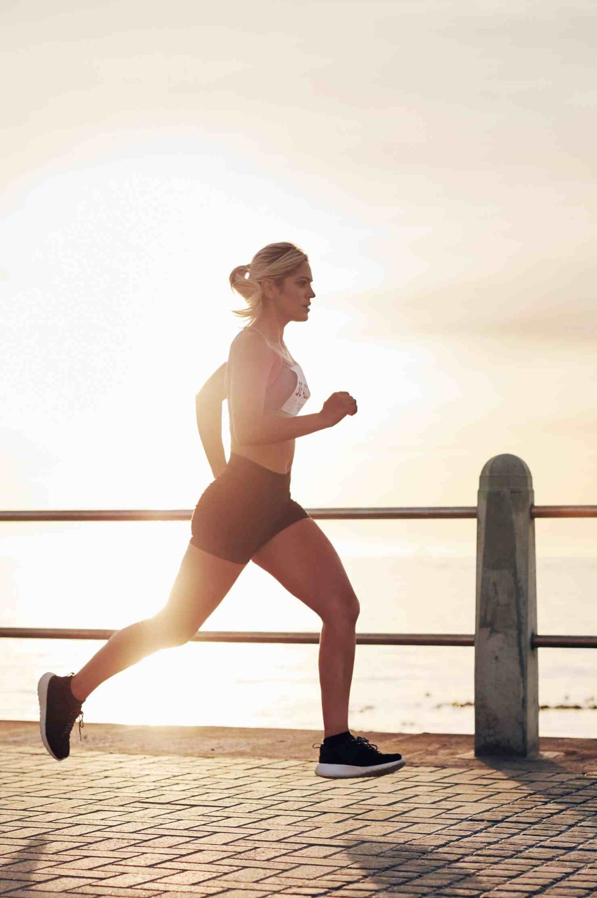 Femme sportive qui court au bord de la mer avec un dossard