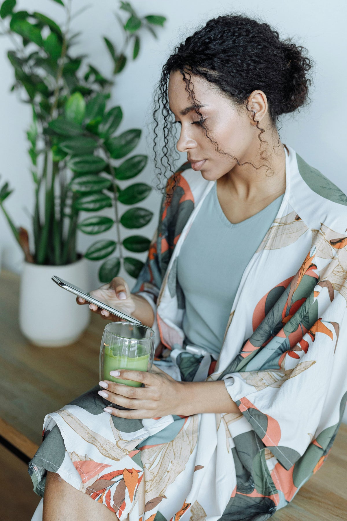 Une femme buvant un matcha latte avec son smartphone