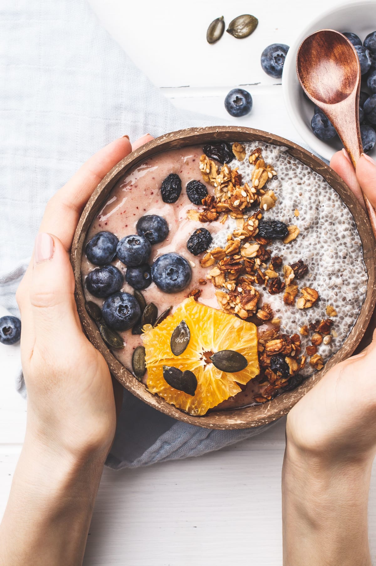 Exemple de petit-déjeuner riche en prébiotiques avec du granola, des graines de chia et courge, myrtilles et orange