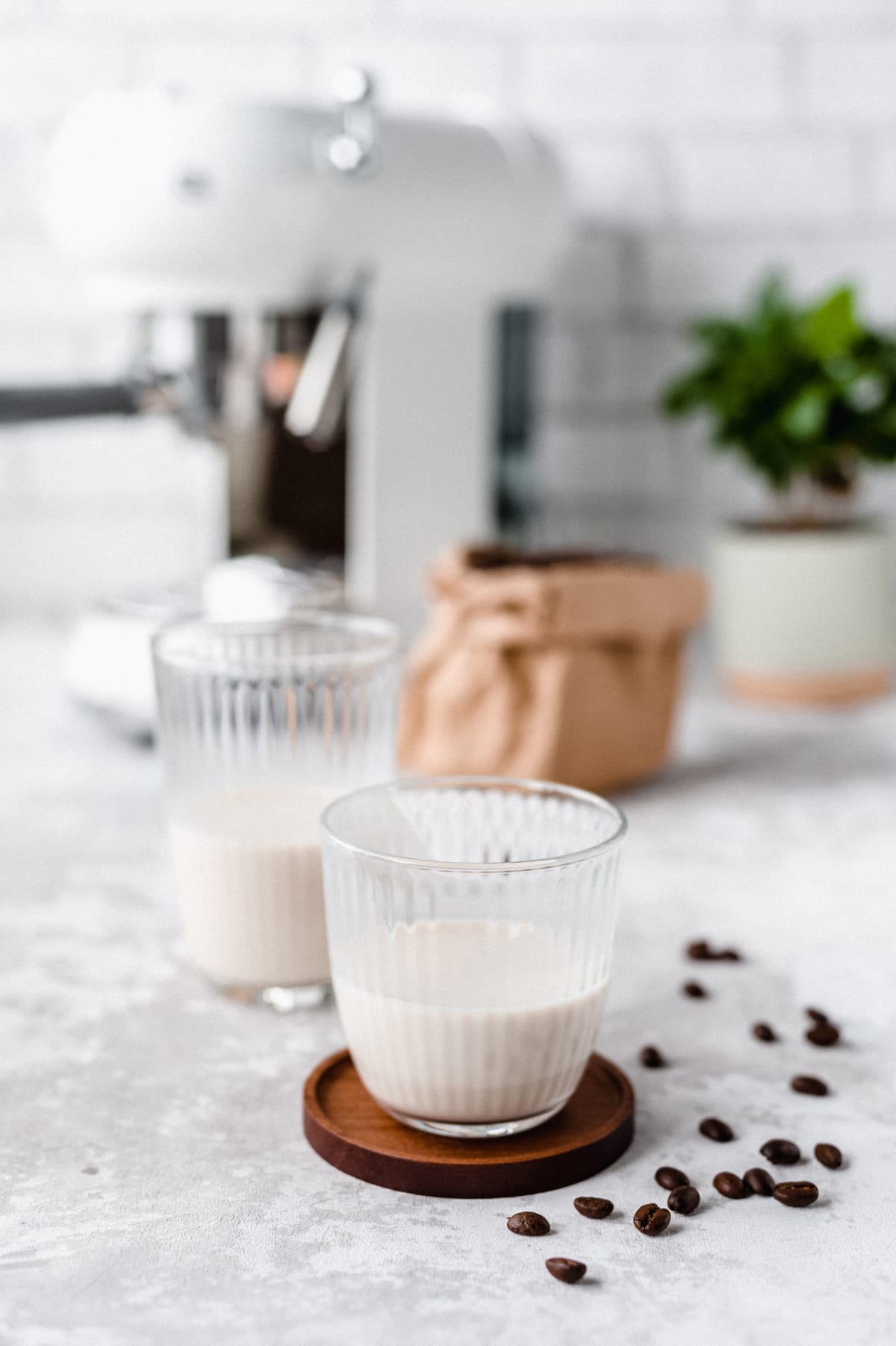 Deux verres de lait végétal sur une table avec des grains de café