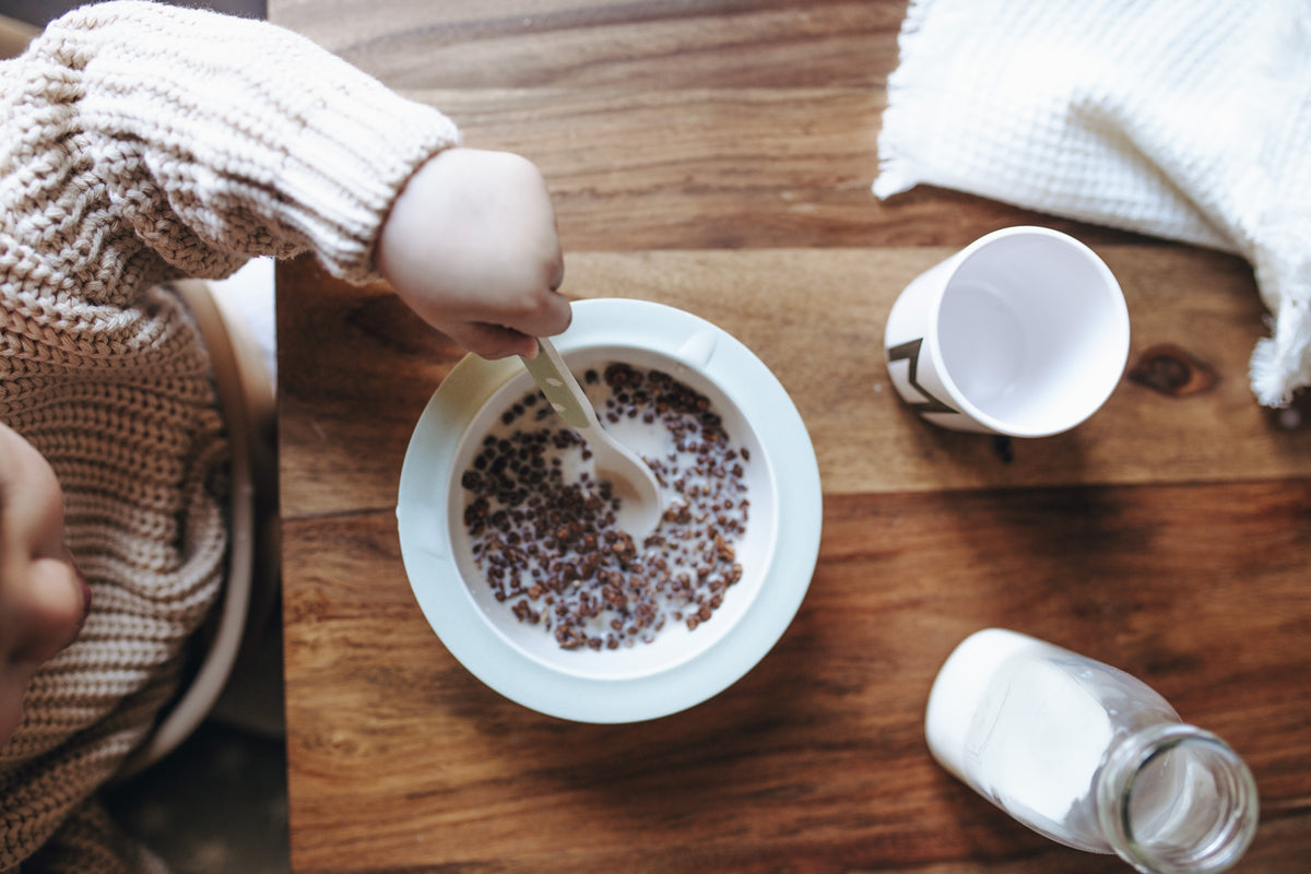 Petit-déjeuner pour enfant avec céréales nümorning, lait végétal et gobelet sur table en bois