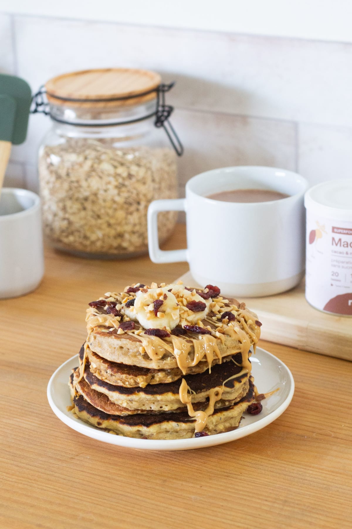 Pile de pancakes garnis de coulis de chocolat, beurre de cacahuète, tranches de banane et granola