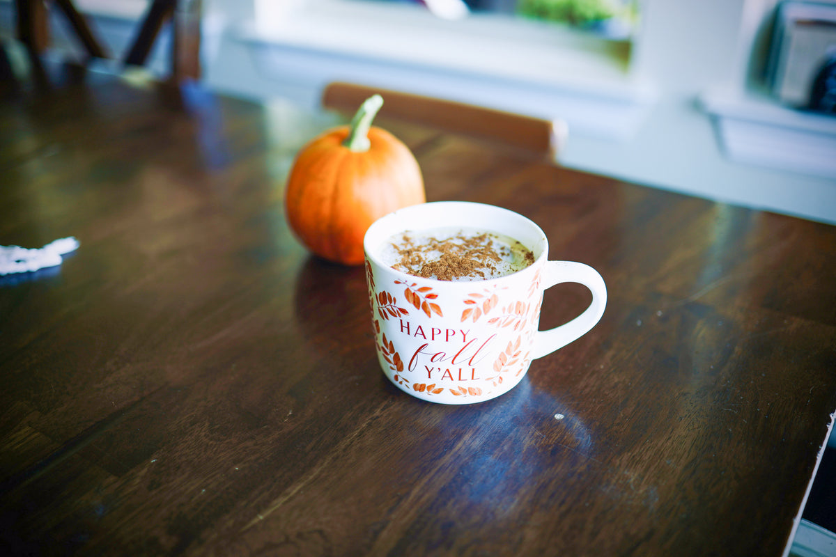 Une tasse de pumpkin latte sur une table à côté d'une citrouille