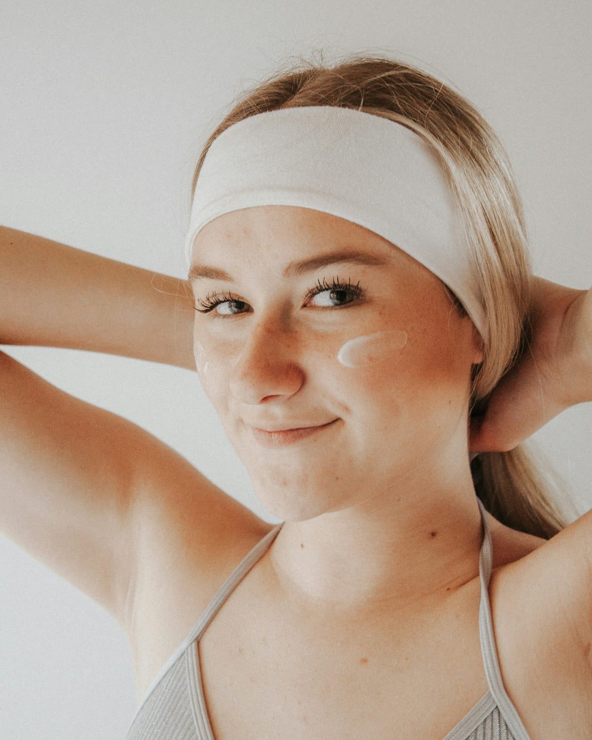 Jeune femme appliquant sa routine in &amp; out pour avoir une belle peau, avec une crème hydratante