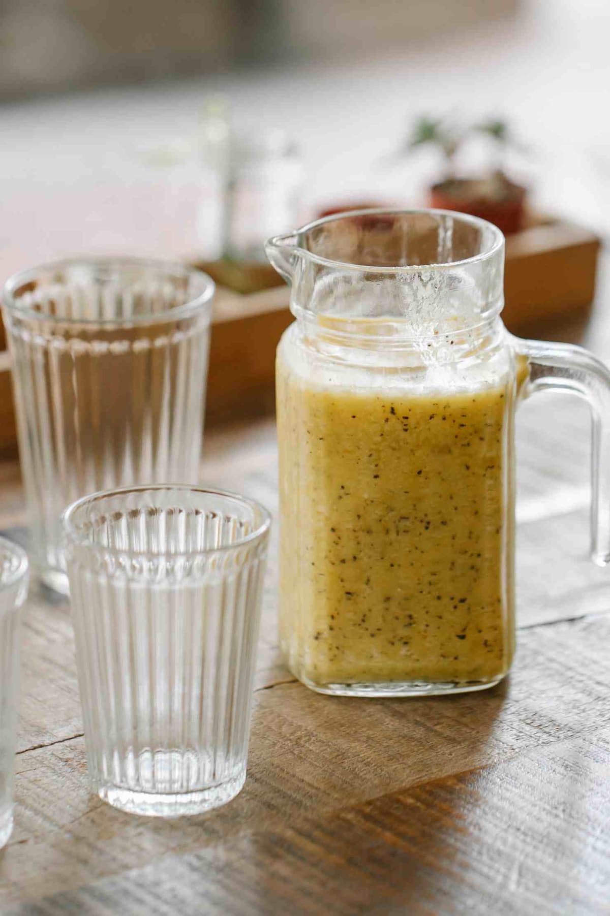 Smoothie dans un pichet avec deux verres sur une table de petit-déjeuner